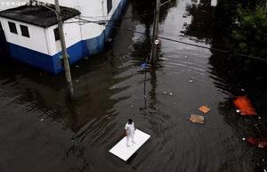 当地时间2017年4月7日，巴西圣保罗，降雨引发洪水淹没街道，一名工人利用桌子在水中移动。