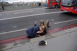 当地时间2017年3月22日，英国伦敦，一名妇女在威斯敏斯特桥上救助伤者。